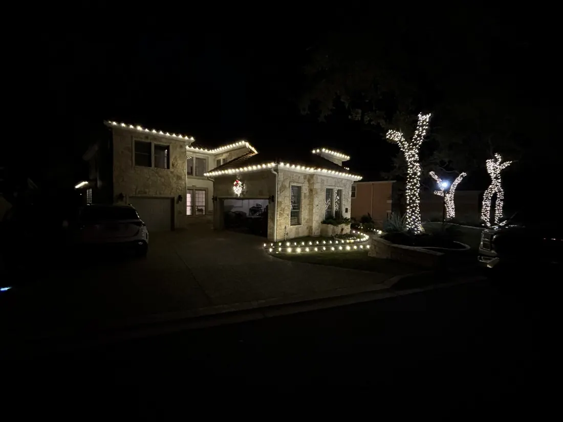 Roofline lights with wrapped trees in the yard